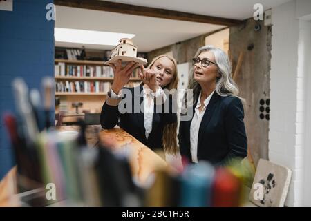 Femme d'affaires mûre et jeune examinant le modèle architectural dans le bureau de loft Banque D'Images