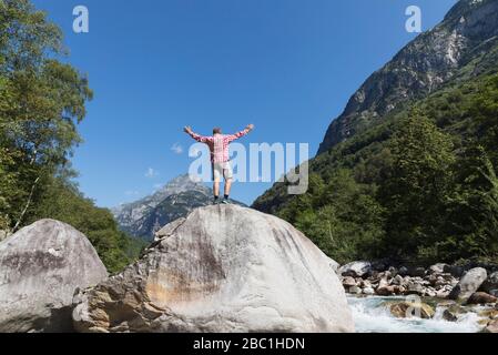 Homme debout sur le rocher de la rivière Verzasca, Verzasca Valley, Tessin, Suisse Banque D'Images