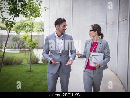 Homme d'affaires et femme d'affaires marchant et parlant sur le trottoir Banque D'Images