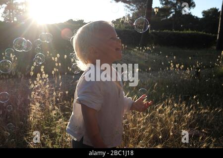 Bonne fille jouant avec des bulles de savon en été Banque D'Images