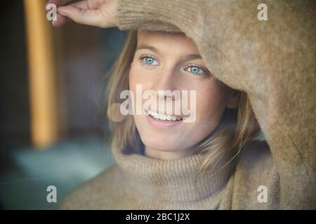 Portrait de la jeune femme blonde souriante derrière le panneau de fenêtre Banque D'Images
