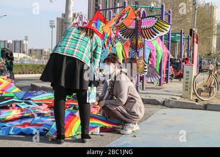 Yinchuan, Chine. 29 mars 2020. Une femme portant un masque de protection a vendu du cerf-volant sur une place publique à Yinchuan. Crédit: SOPA Images Limited/Alay Live News Banque D'Images