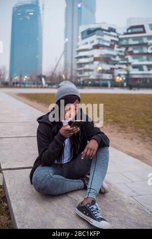 Jeune femme utilisant un smartphone dans la ville au crépuscule Banque D'Images