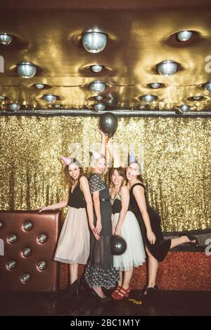 Portrait de quatre femmes heureuses portant des chapeaux de fête dans un club Banque D'Images