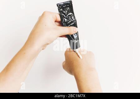 Mains application de crème hydratante à partir du tube noir après lavage des mains et utilisation de gel d'alcool pendant l'épidémie de virus. Traitement pour la peau sèche. Peau de luxe Banque D'Images