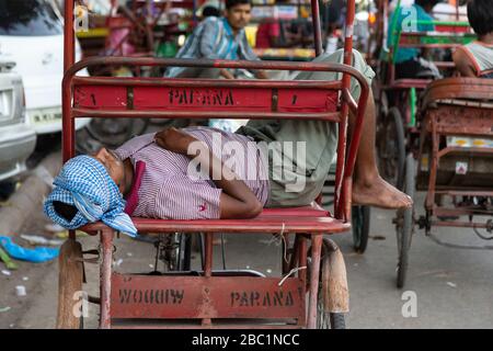 Chauffeur dormant sur son vélo pousse-pousse à Old Delhi, Inde Banque D'Images