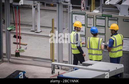 Le superviseur et les travailleurs examinent les informations sur le mur en usine Banque D'Images