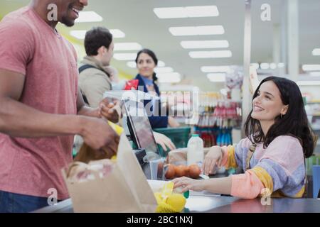 Un caissier sympathique aide les clients au moment de la commande au supermarché Banque D'Images