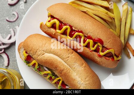 Délicieux hot dogs et pommes de terre frites sur une table grise, vue sur le dessus Banque D'Images