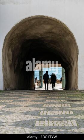 Silhouette d'un couple marchant à travers un tunnel piétonnier à la plage d'Albufeira dans l'Algarve, au Portugal Banque D'Images