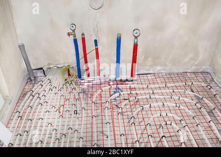 Tuyaux avec de l'eau chaude et froide sortant du plancher et manomètres montés aux extrémités des tuyaux pour vérifier le serrage du système. Banque D'Images