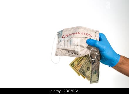 Main avec des billets de dollar et un masque de visage avec le mot coronavirus isolé sur blanc Banque D'Images