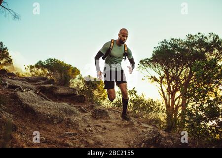 Homme courir sur un sentier rocheux de montagne. Coureur masculin en pente dure le matin. Banque D'Images