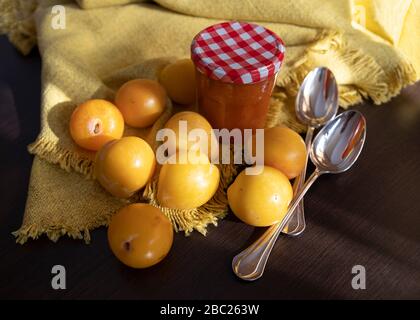 Gros plan de prunes jaunes et un pot de confiture sur fond en bois et jaune Banque D'Images