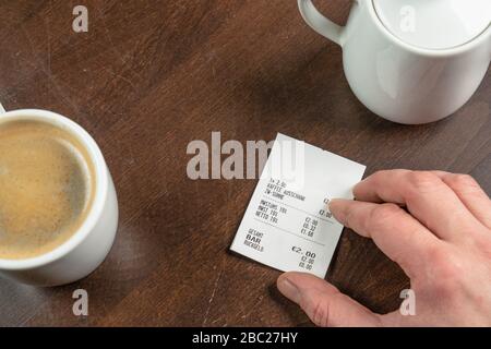 une main tient un reçu sur une table en bois Banque D'Images