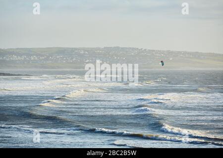 Un kitesurfer navigue sur les vagues de Porthcawl, Pays de Galles, Royaume-Uni Banque D'Images