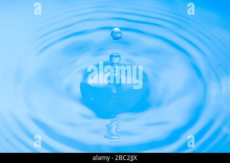 Goutte d'eau tombe dans l'eau bleue Banque D'Images