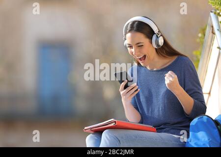 Enchanté par les étudiants qui ont vérifié leur smartphone assis sur un campus une journée ensoleillée Banque D'Images