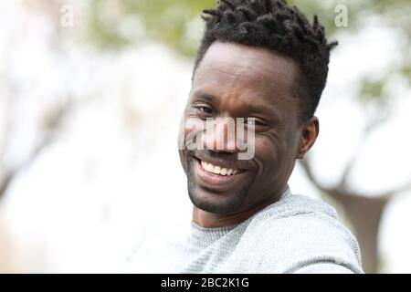 Portrait d'un homme noir heureux avec des dents blanches parfaites sourire regardant l'appareil photo au parc Banque D'Images