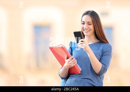 Heureux étudiant en vérifiant le contenu en ligne du téléphone mobile sur un campus Banque D'Images