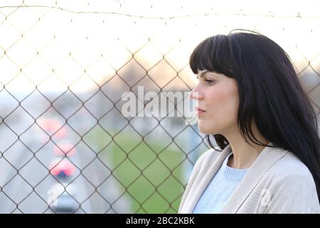 Profil d'une femme pensive inquiète regardant loin sur un pont au-dessus de la route Banque D'Images