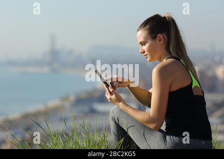 Un coureur sérieux qui vérifia le smartphone après avoir fait du sport à l'extérieur dans une banlieue de la ville Banque D'Images