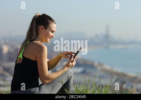 Bonne femme coureur qui consulte l'application smartphone située à la périphérie de la ville Banque D'Images