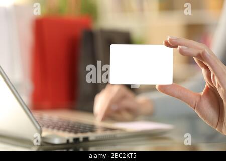 Gros plan sur la main de la femme cashopper montrant une carte de crédit vierge payant sur un ordinateur portable sur un bureau à la maison avec des sacs sur l'arrière-plan Banque D'Images