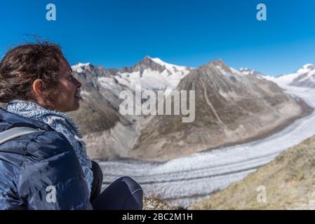Une jeune femme est assise en regardant le glacier du Grand Aletsch. Suisse. C'est le plus long glacier des Alpes. Banque D'Images