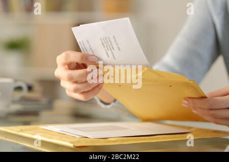 Gros plan sur les mains d'une femme ouvrant une lettre sur une enveloppe rembourrée sur un bureau à la maison Banque D'Images