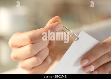 Gros plan sur les mains d'une femme mettant un trombone argenté sur les feuilles de document Banque D'Images