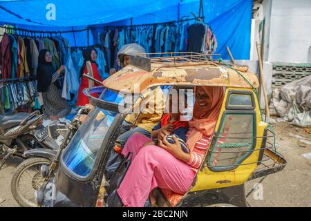 21 juin 2018 Panyambungan, Sumatra, Indonésie : mère locale et fils petit enfant assis dans un taxi fou de moto becak. Tacheté près du marché dans la rue Banque D'Images