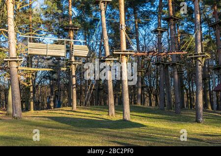 Jardin d'escalade, parcours de cordes dans la forêt avec divers éléments d'escalade et cordes de sécurité entre les arbres individuels et les bancs pour se reposer Banque D'Images