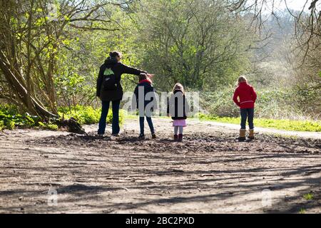 Mère et 3 enfants trois filles enfants marchent / marchent le long du sentier boueux / dans la boue sur le sentier de passerelle chemin de pied sentier. West End Common, près d'Esher, Surrey. ROYAUME-UNI (116) Banque D'Images