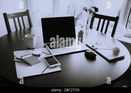 Travailler de la maison avec un ordinateur portable, une tasse à café, une souris et un bloc-notes avec travail de la maison écrit sur une table à manger Suède, Göteborg Banque D'Images