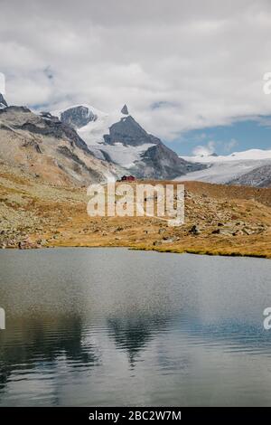 Les petits touristes rouges abritent la maison et le magnifique lac de montagnes avec des pics enneigés de réflexion des Alpes suisses Banque D'Images