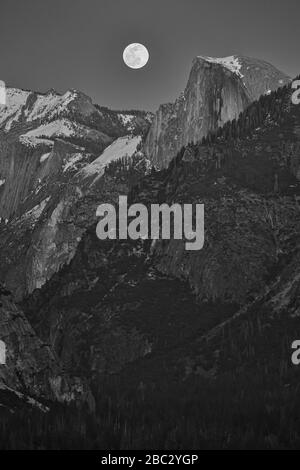 Une image en noir et blanc de la lune qui s'élève au-dessus du demi-dôme dans le parc national de Yosemite, États-Unis Banque D'Images