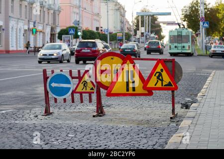 Des panneaux d'avertissement et des clôtures dans le secteur de la route travaillent dans une rue animée. Banque D'Images