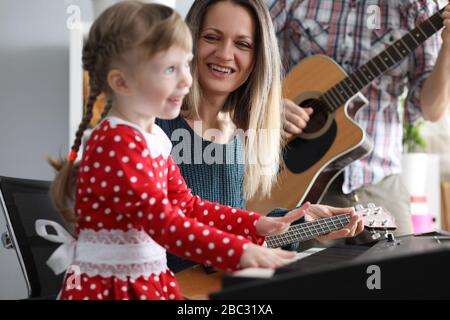 Les parents jouent des guitares, fille sur synthétiseur Banque D'Images