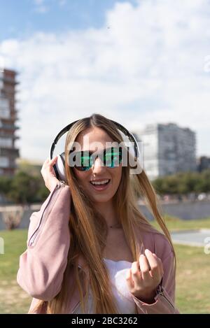 La jeune fille caucasienne aime écouter de la musique dans un parc de la ville. Banque D'Images