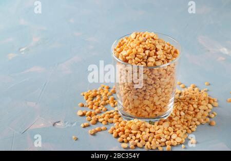 Grains de pois secs dans un verre et une table sur fond bleu clair Banque D'Images