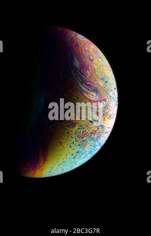 Macrophotographie d'une bulle de savon colorée ressemble à une planète avec un croissant d'ombre Banque D'Images