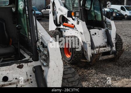 Deux mini-chargeuses blanches sur un chantier en attente de travail. Machines industrielles. Industrie. Banque D'Images