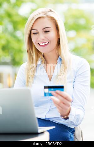 Jeune femme d'affaires utilisant un ordinateur portable et tenant une carte de crédit Banque D'Images