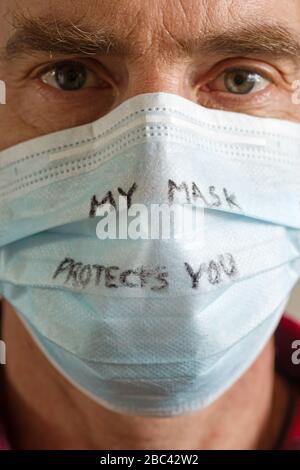 homme d'âge moyen avec masque de visage qui dit que mon masque vous protège écrit en stylo noir dessus Banque D'Images