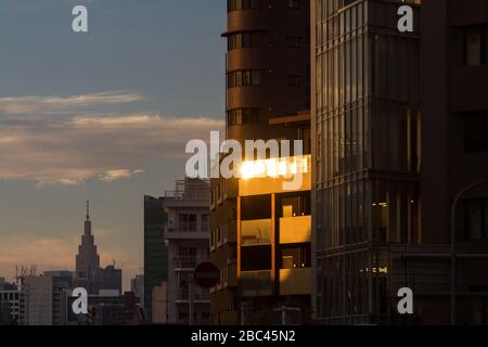 Le bâtiment caractéristique de NTT DoCoMo Yoyogi au loin, tandis que la lumière du coucher du soleil s'empare sur les fenêtres de Roppongi, Tokyo, Japon. Banque D'Images