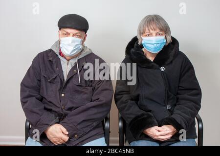 Un couple de personnes âgées porte des masques en salle d'attente Banque D'Images