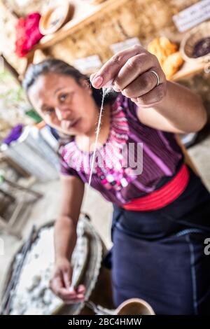 Une jeune femme tourne le coton dans une coopérative du village de San Juan sur la rive du lac Atitlan, au Guatemala. Banque D'Images