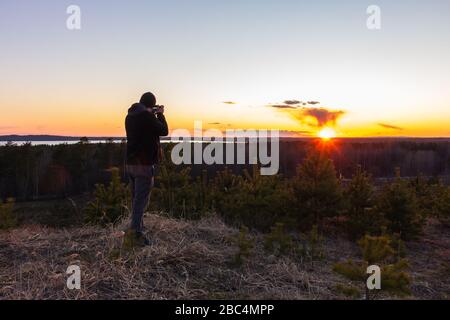 le photographe prend un coucher de soleil sur une montagne Banque D'Images