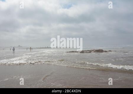 Les habitants de la région se divertissent en eau peu profonde au bord de l'eau sur la plage publique de Casablanca, au Maroc. Banque D'Images